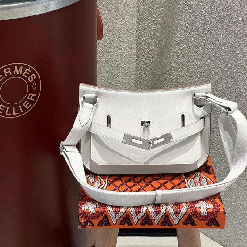 A clean white leather Gypsy shoulder bag with silver-tone hardware, displayed on an artistic orange beaded stand next to a decorative burgundy cylinder.