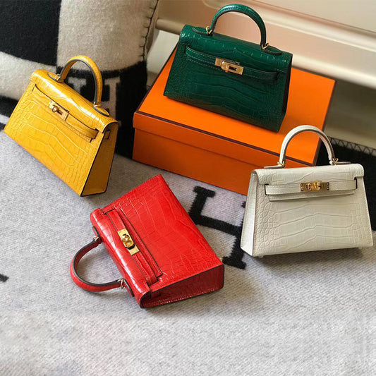 Four mini Kelly handbags in yellow, green, red, and white croc-embossed leather with gold-tone locks.
