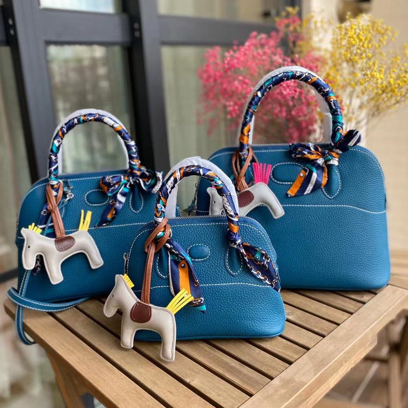 Three sizes of teal blue leather bowling shell bags comparison with silk scarves