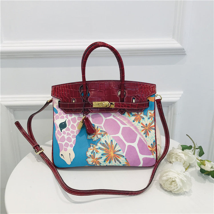 This Birkin-style bag is crafted from top-grain cowhide and features a graffiti art print and gold-tone hardware.