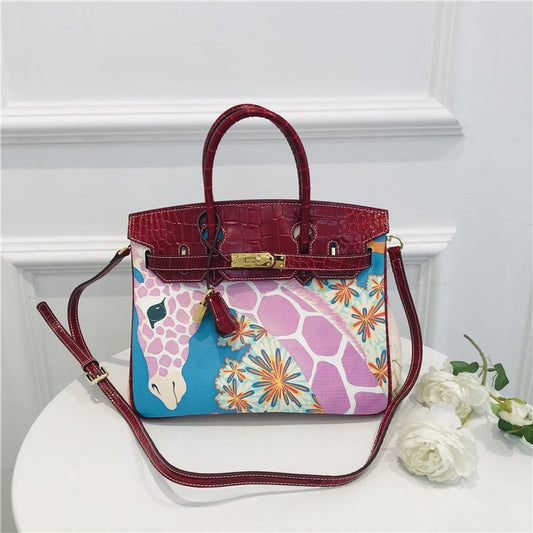 This Birkin-style bag is crafted from top-grain cowhide and features a graffiti art print and gold-tone hardware.
