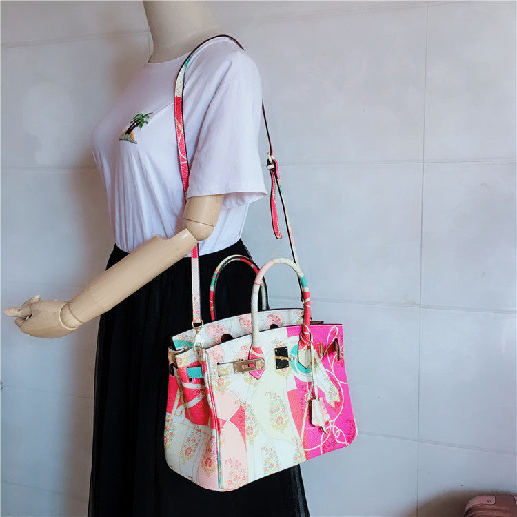 This Birkin-style bag is crafted from top-grain cowhide and features a graffiti art print and gold-tone hardware.