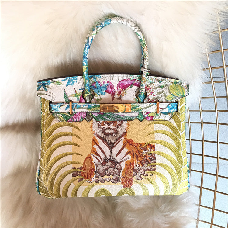 This Birkin-style bag is crafted from top-grain cowhide and features a graffiti art print and gold-tone hardware.
