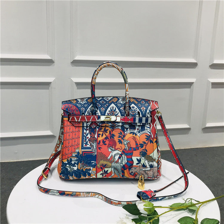 This Birkin-style bag is crafted from top-grain cowhide and features a graffiti art print and gold-tone hardware.