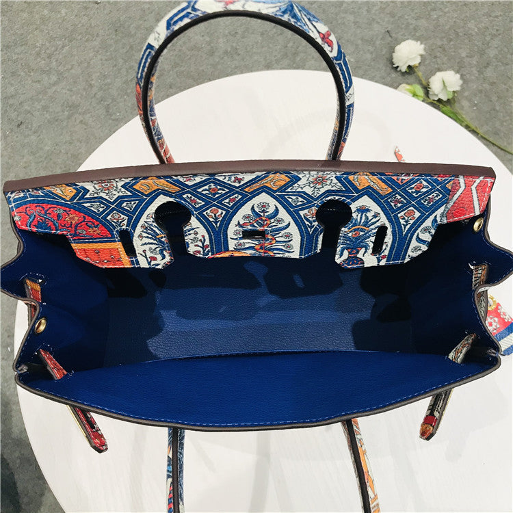 This Birkin-style bag is crafted from top-grain cowhide and features a graffiti art print and gold-tone hardware.