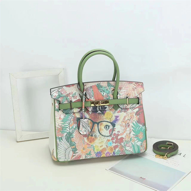 This Birkin-style bag is crafted from top-grain cowhide and features a graffiti art print and gold-tone hardware.