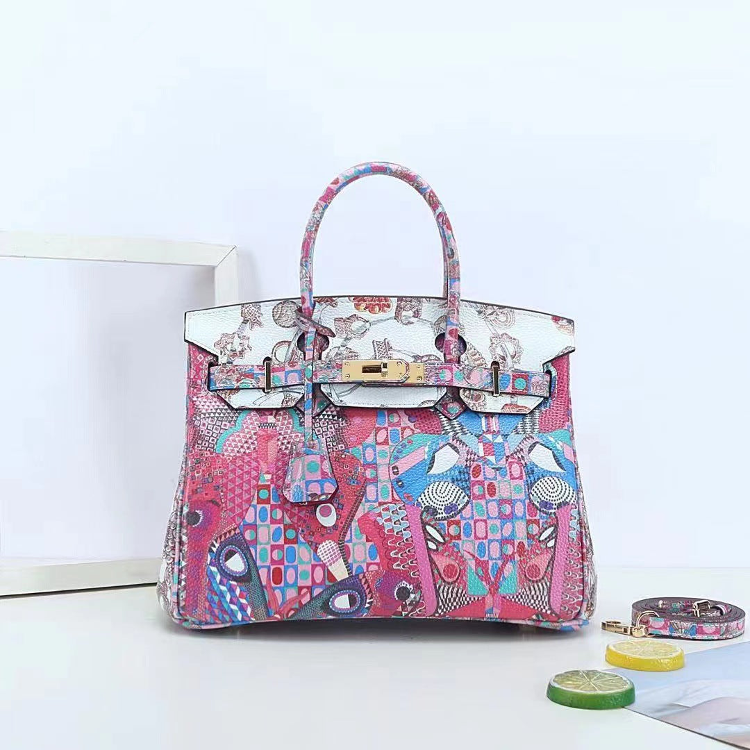 This Birkin-style bag is crafted from top-grain cowhide and features a graffiti art print and gold-tone hardware.