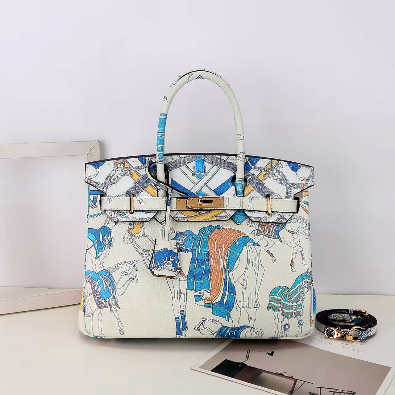 This Birkin-style bag is crafted from top-grain cowhide and features a graffiti art print and gold-tone hardware.