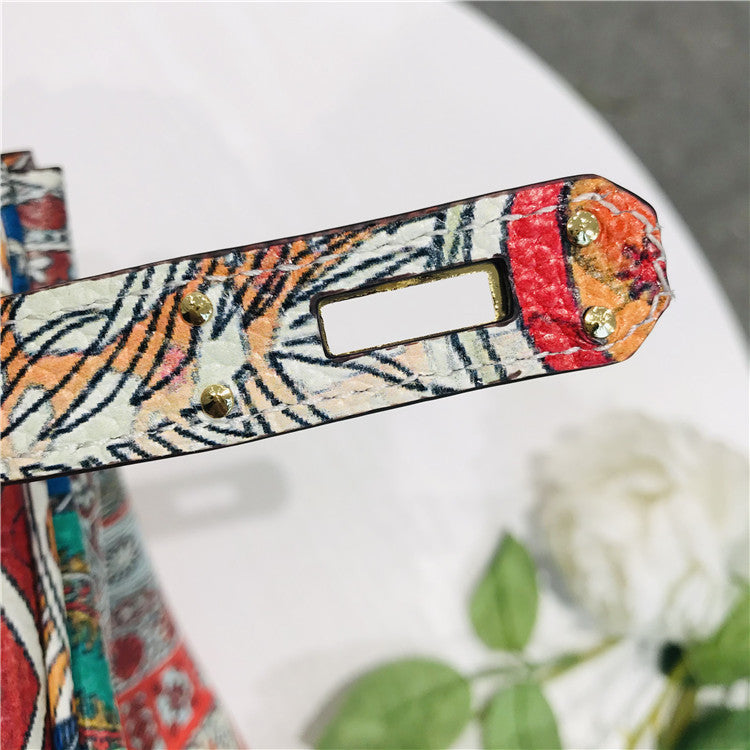 Colorful patterned strap with gold accents on a white surface with a blurred background