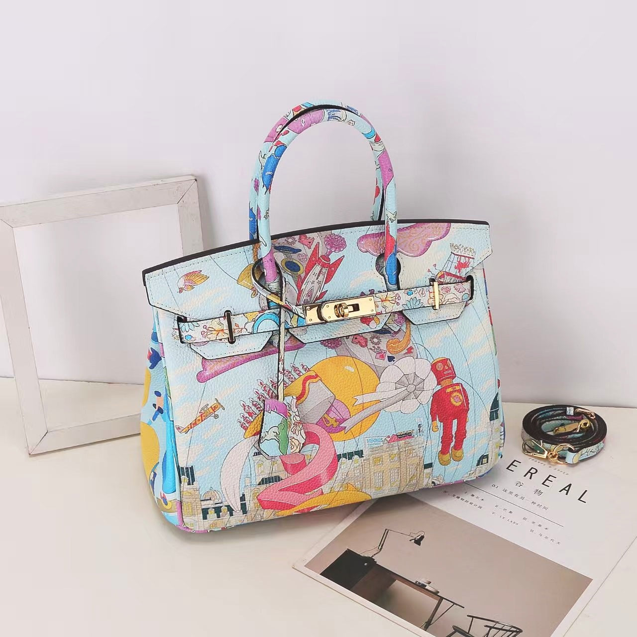 This Birkin-style bag is crafted from top-grain cowhide and features a graffiti art print and gold-tone hardware.