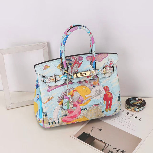 This Birkin-style bag is crafted from top-grain cowhide and features a graffiti art print and gold-tone hardware.