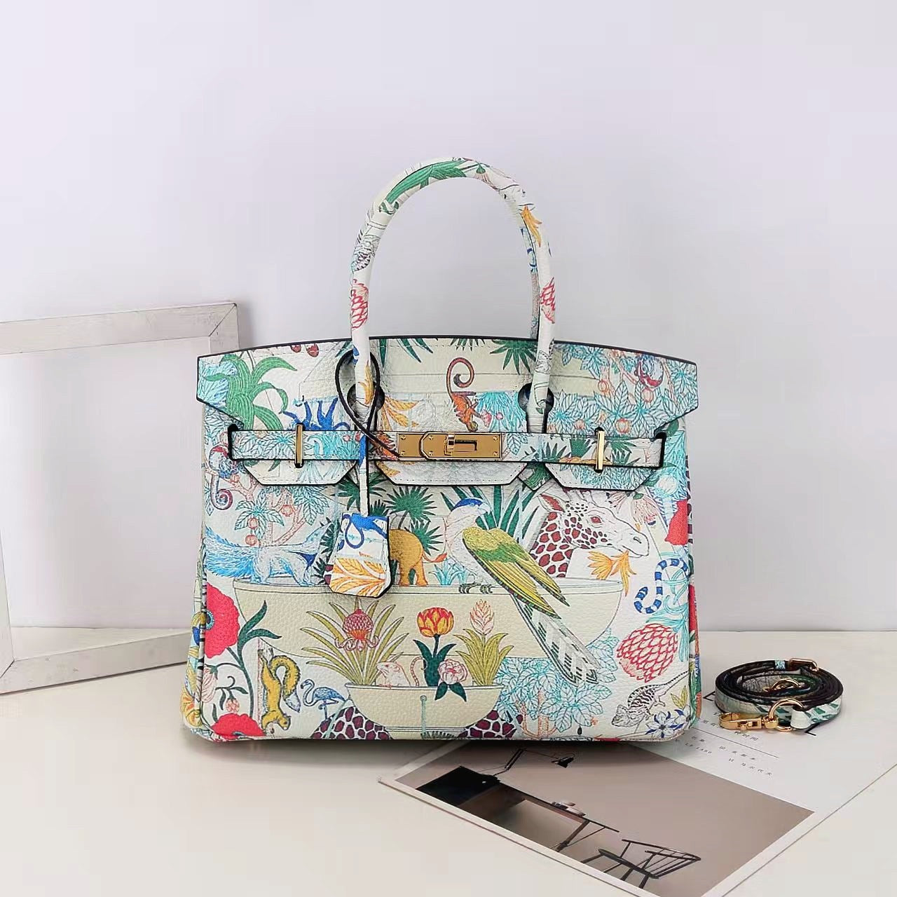 This Birkin-style bag is crafted from top-grain cowhide and features a graffiti art print and gold-tone hardware.