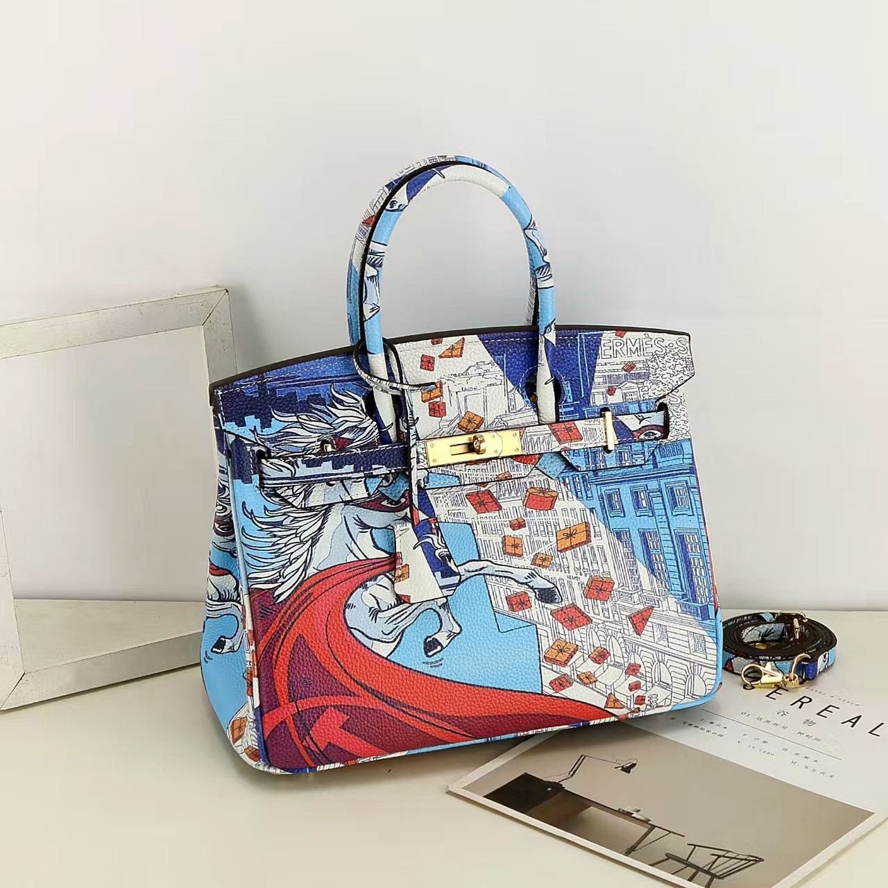 This Birkin-style bag is crafted from top-grain cowhide and features a graffiti art print and gold-tone hardware.