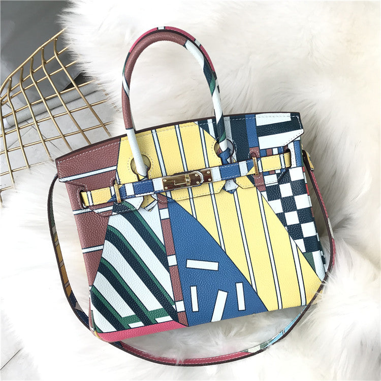 This Birkin-style bag is crafted from top-grain cowhide and features a graffiti art print and gold-tone hardware.