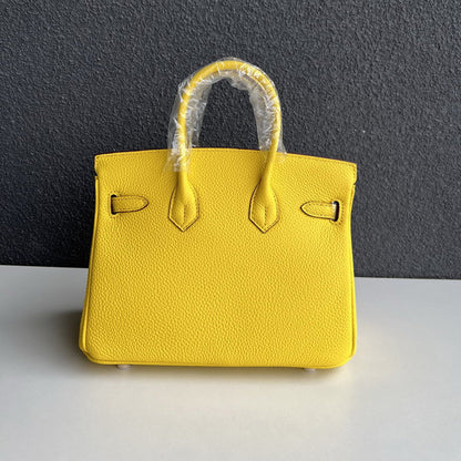 Back view of yellow genuine leather handbag with double handles.