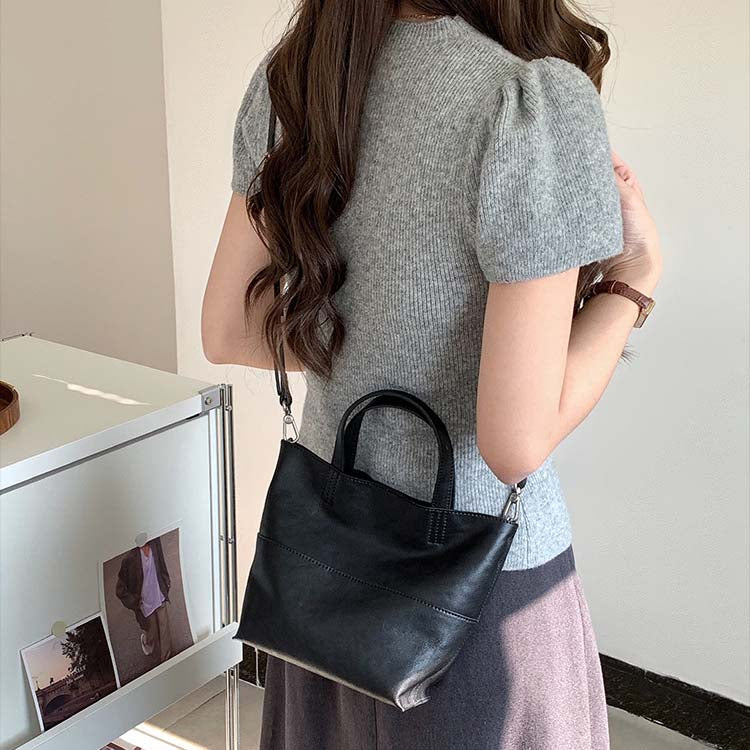 A black, high-quality cowhide mini tote bag paired with a grey knit top.