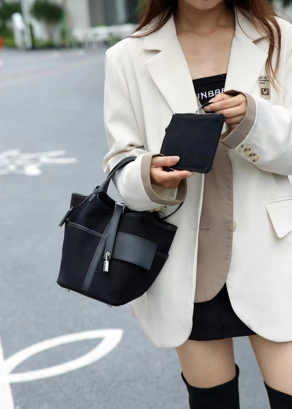 Close-up street shot of a black Cargo Pictin 18 handbag in leather and canvas, featuring the silver lock and matching mini pouch.