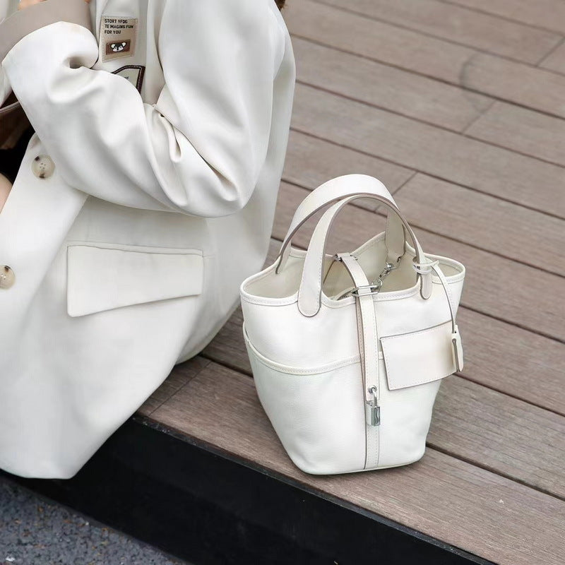 Outdoor shot of a white Cargo Pictin 18 handbag in leather and canvas placed on wooden stairs, showcasing its elegant structured design and silver lock.