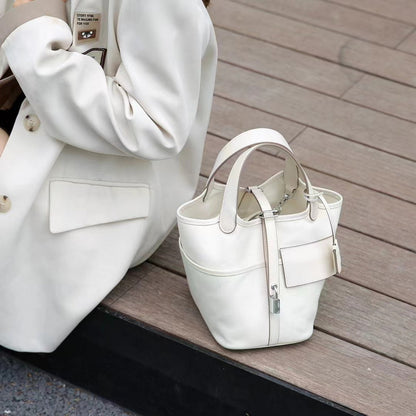 Outdoor shot of a white Cargo Pictin 18 handbag in leather and canvas placed on wooden stairs, showcasing its elegant structured design and silver lock.