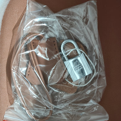 Close-up of the silver padlock accessory and leather key clochette for the Cargo Pictin 18 handbag, shown in protective packaging.