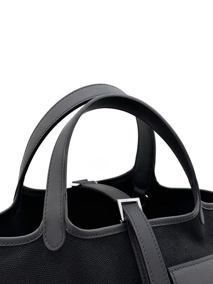 Close-up of the leather handles and canvas texture on a black Cargo Pictin 18 handbag, featuring precise stitching details.