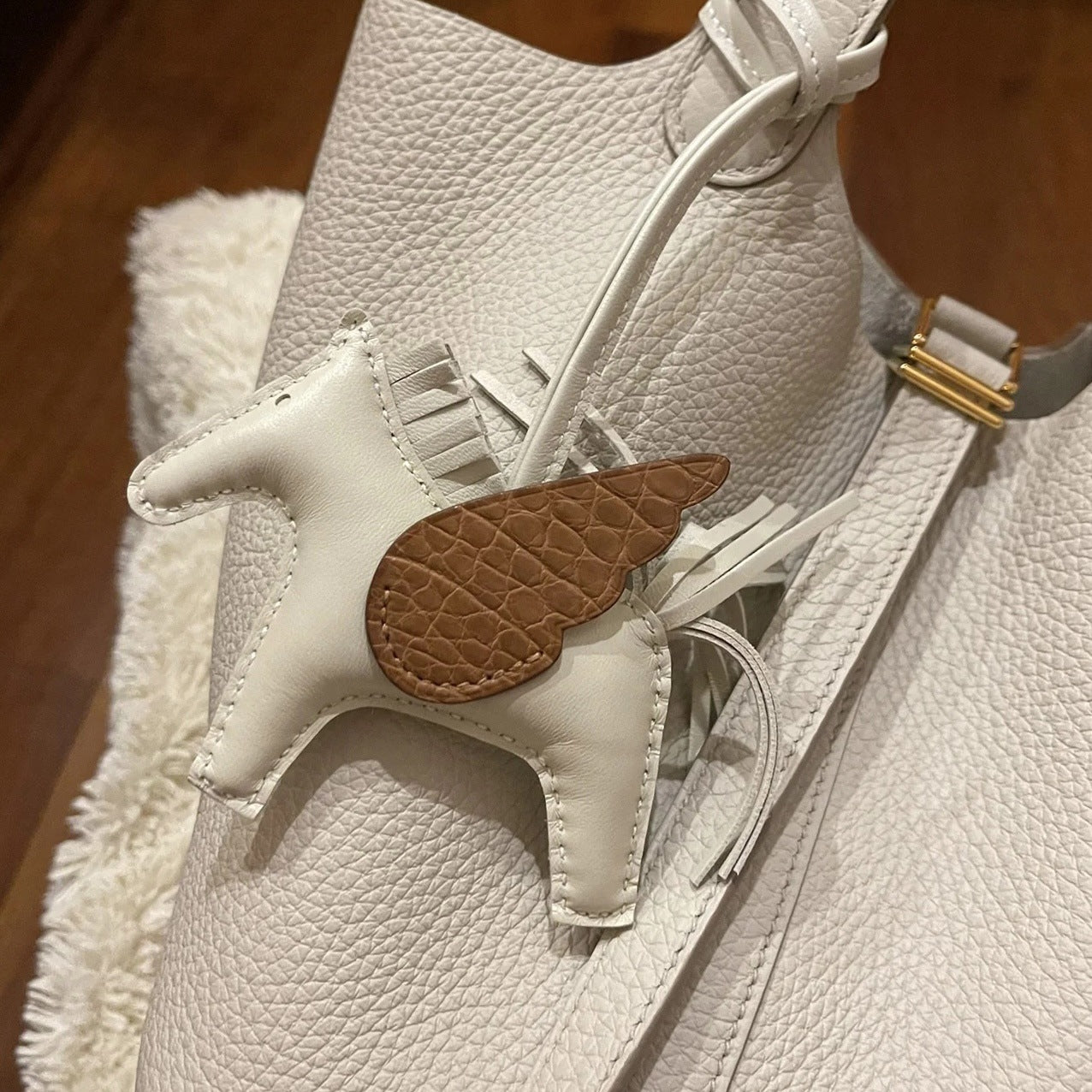 Off-white Pegasus charm with brown crocodile-pattern wings on matching pebble leather bag.