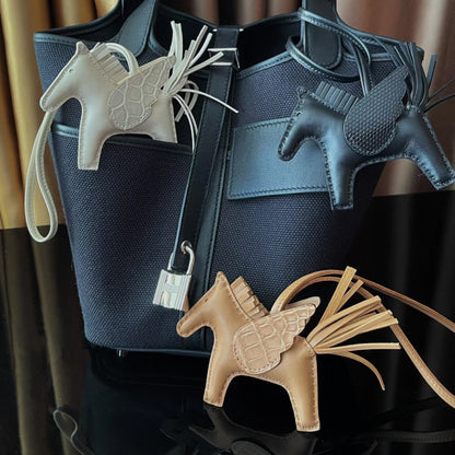 Collection of Pegasus horse charms in white, black, and tan leather with crocodile-pattern wings.