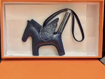 Navy blue lambskin Pegasus charm with matching crocodile-pattern wings in an orange gift box.