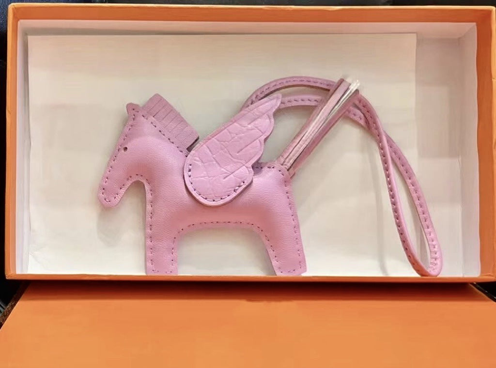 Pink lambskin Pegasus charm with crocodile-pattern wings in an orange gift box.