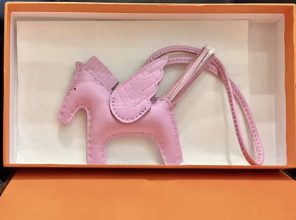 Pink lambskin Pegasus charm with crocodile-pattern wings in an orange gift box.