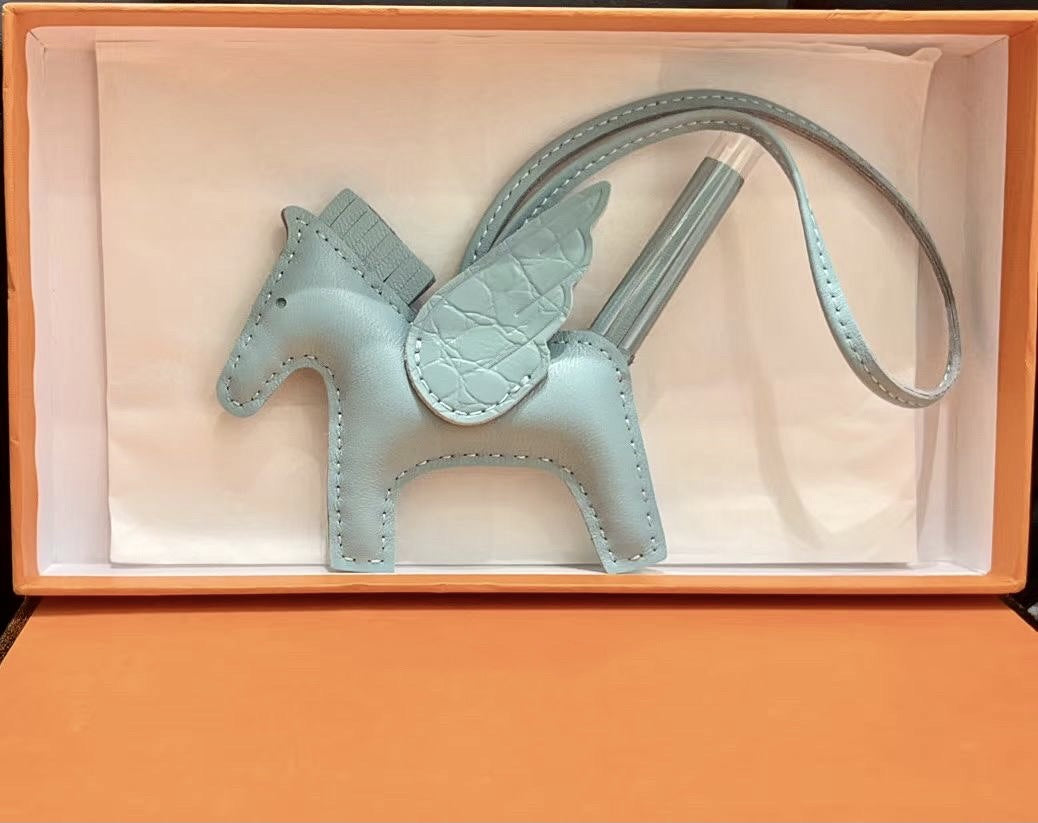 Light blue lambskin Pegasus charm with crocodile-pattern wings in an orange gift box.