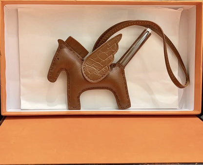 Brown lambskin Pegasus charm with crocodile-pattern wings in an orange gift box.