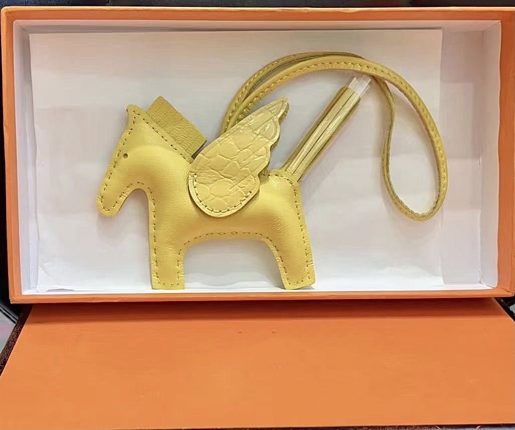 Yellow lambskin Pegasus charm with crocodile-pattern wings in an orange gift box.