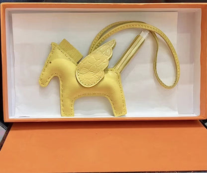 Yellow lambskin Pegasus charm with crocodile-pattern wings in an orange gift box.
