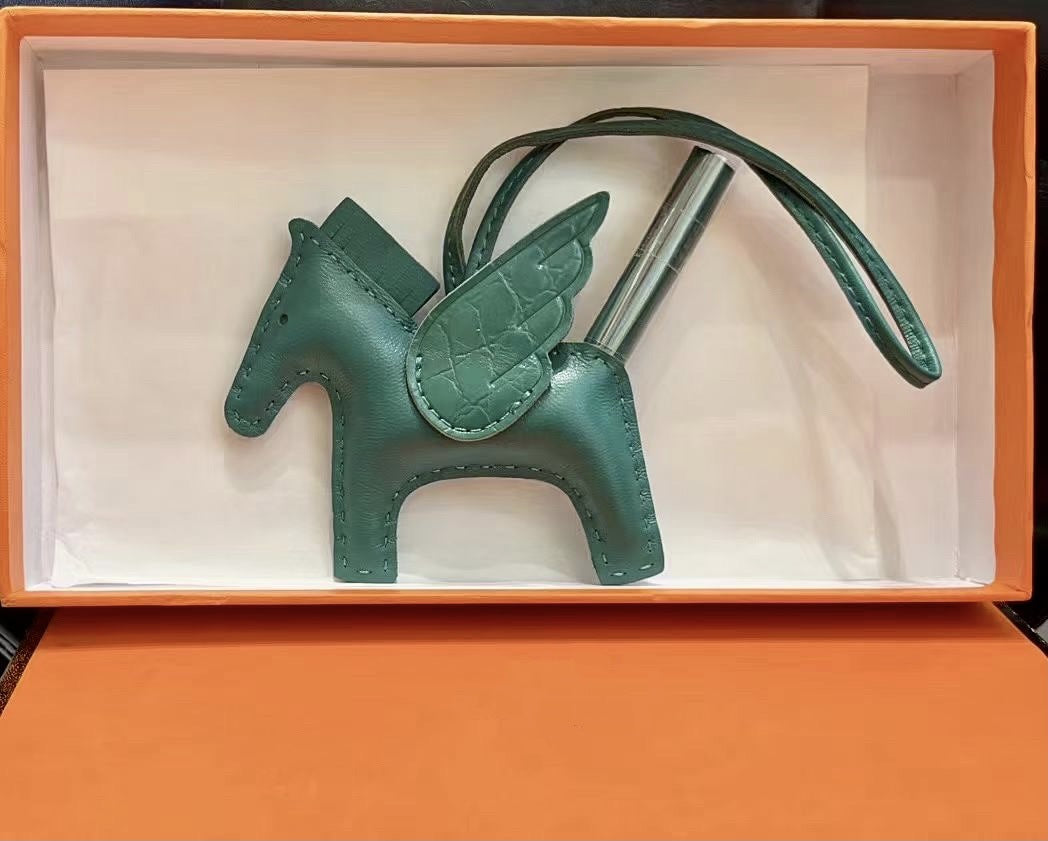 Dark green lambskin Pegasus charm with matching crocodile-pattern wings in an orange gift box.