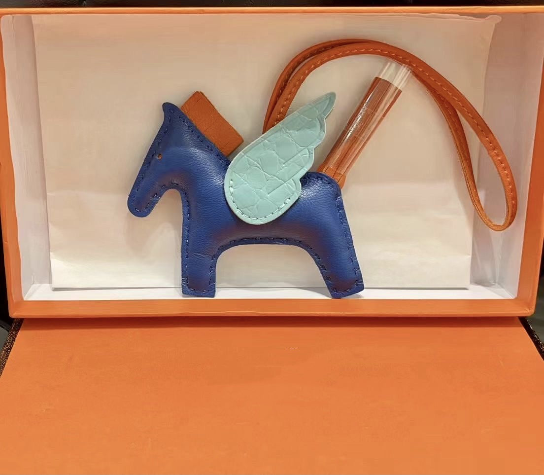 Tricolor Pegasus charm with royal blue body, light blue crocodile-pattern wings, and orange strap.