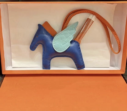 Tricolor Pegasus charm with royal blue body, light blue crocodile-pattern wings, and orange strap.