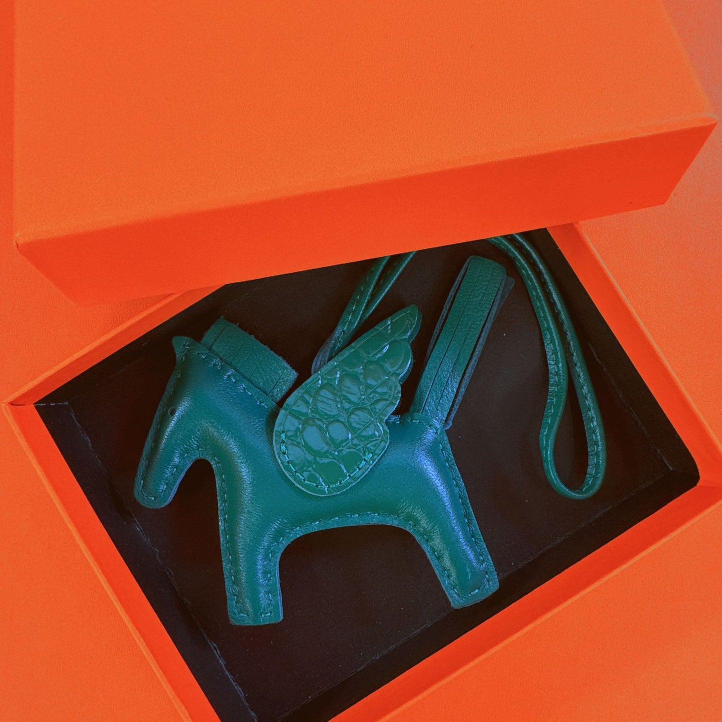 Emerald green lambskin Pegasus charm with matching crocodile-pattern wings in an orange gift box.