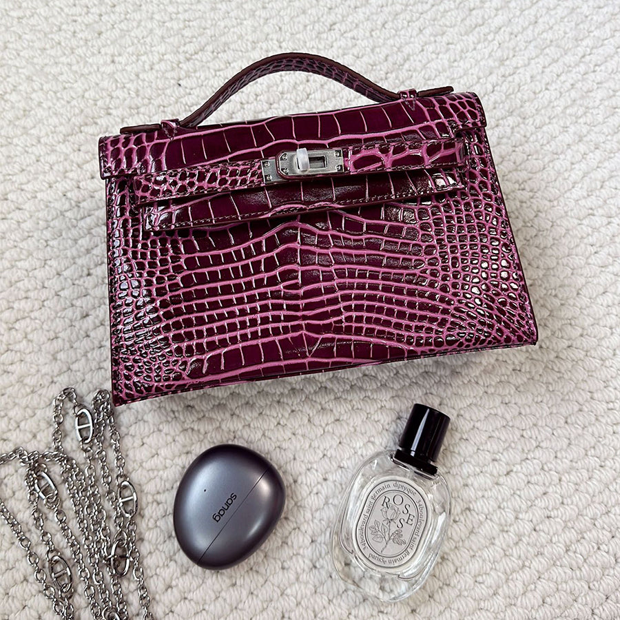 Burgundy crocodile embossed leather Kelli clutch bag with chain strap and silver hardware.