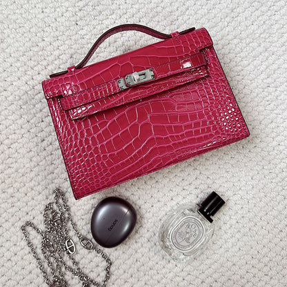 Rosy crocodile embossed leather Kelli clutch bag with chain strap and silver hardware.