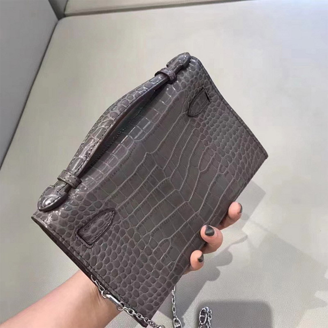Back view of grey crocodile embossed leather Kelli clutch showing texture and strap.