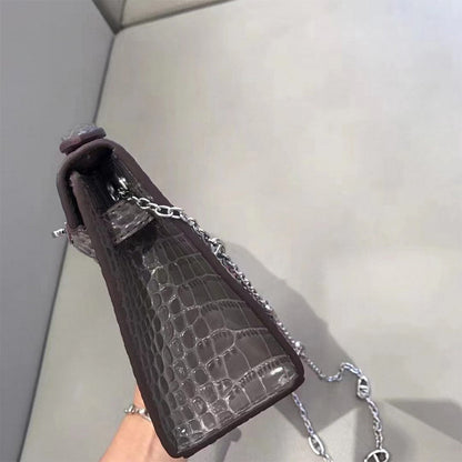 Side view of grey crocodile embossed leather Kelli clutch showing gusset and chain.