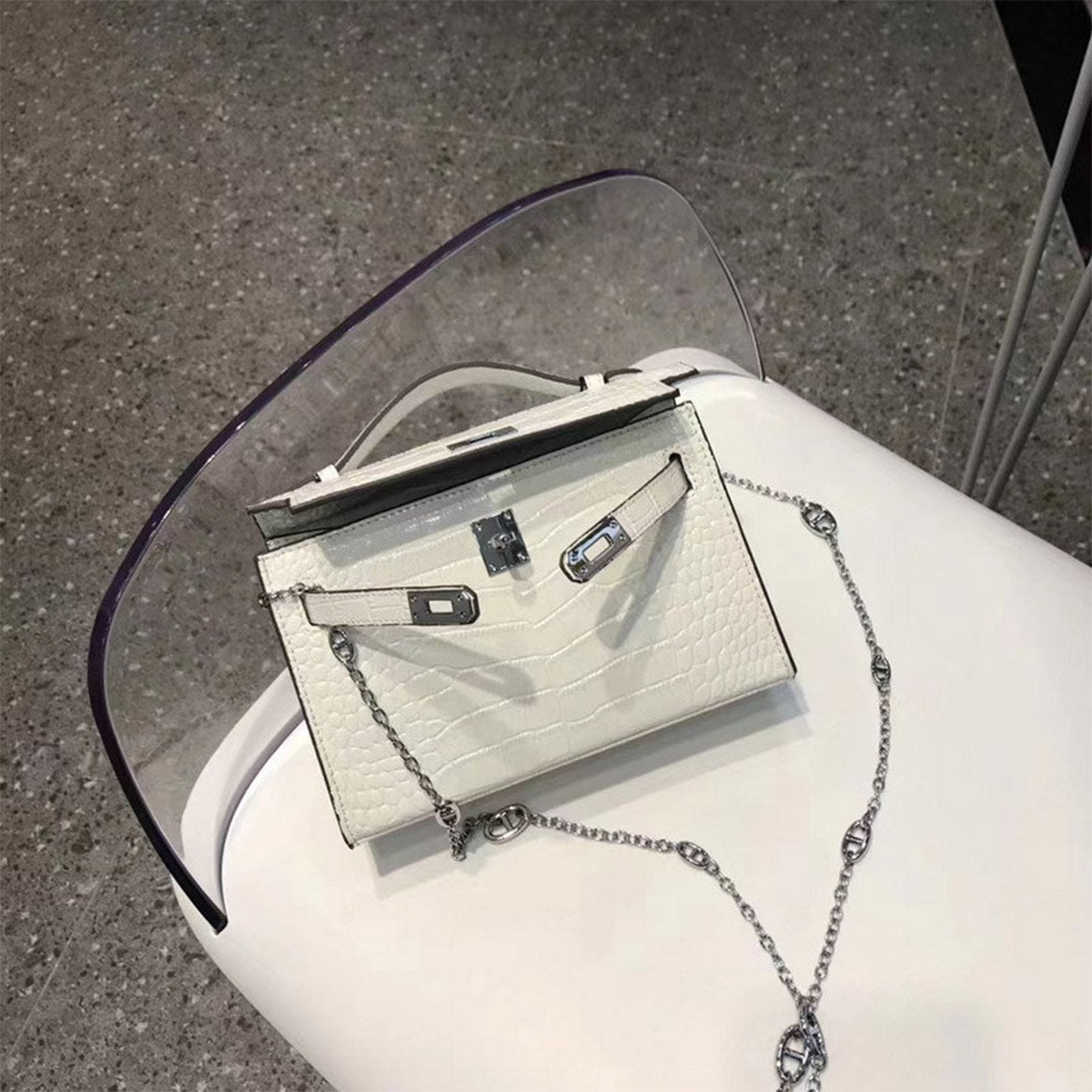 White crocodile embossed leather Kelli clutch bag with silver hardware and chain strap.