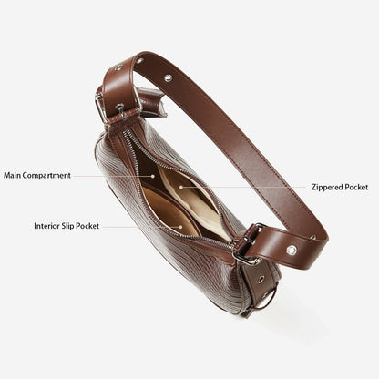 A top-down view of a brown crocodile-embossed leather bag, showcasing its multi-layered interior: featuring a main compartment, a zippered pocket, and an interior slip pocket.