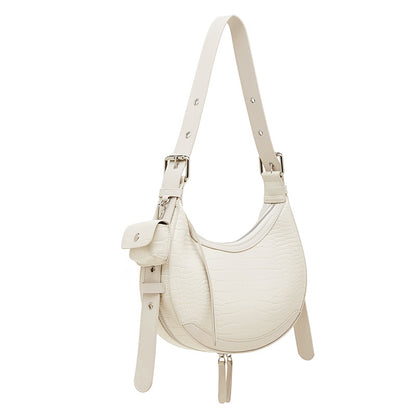A vintage-style beige crocodile-embossed shoulder bag, featuring a unique crescent silhouette accented by a silver-tone metal buckle, and detailed with a detachable side-hanging earbud/coin pouch.