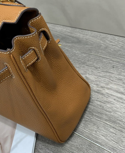 Side view of a tan mini Kelli bag crafted from top grain leather with visible white contrast stitching and pebbled texture.