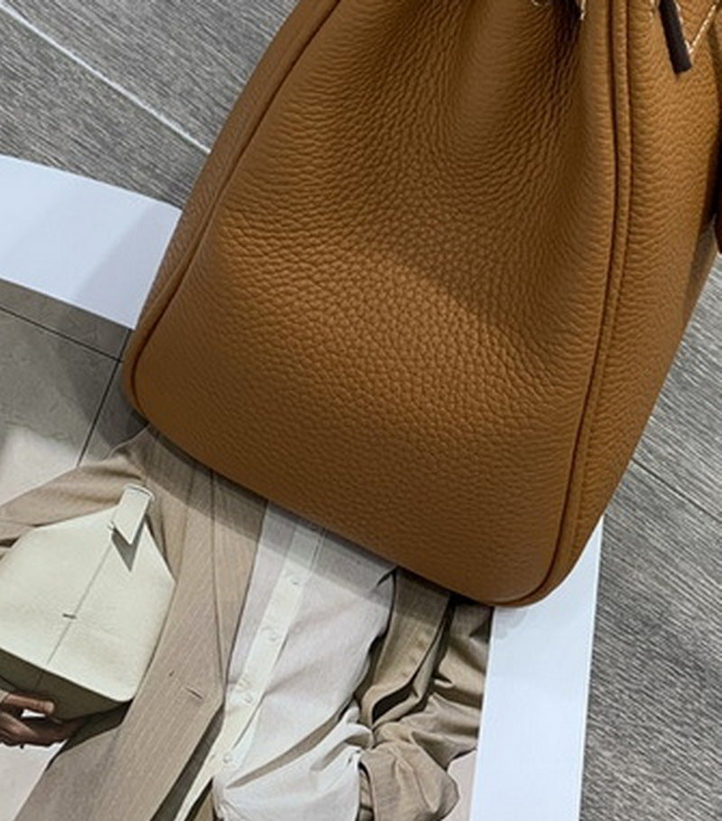 Close-up of the bottom corner of a tan mini Kelli bag, highlighting the premium grained leather texture and structured design.