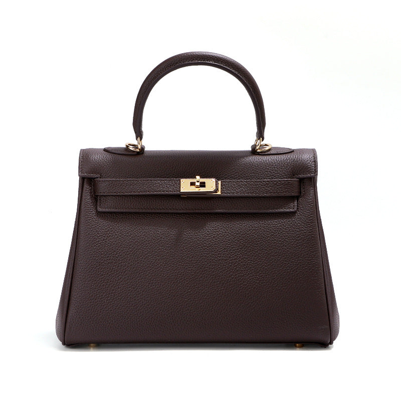 A trapezoid shape, a single top handle and a shoulder strap, carry this timeless inspired Kelli bag in style.