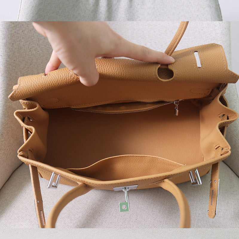 Interior view of a tan JPG Birkin inspired handbag in top grain cowhide leather, featuring a spacious main compartment, a zippered pocket, and an open slip pocket.