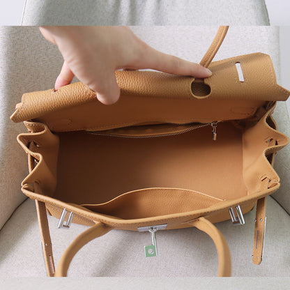 Interior view of a tan JPG Birkin inspired handbag in top grain cowhide leather, featuring a spacious main compartment, a zippered pocket, and an open slip pocket.